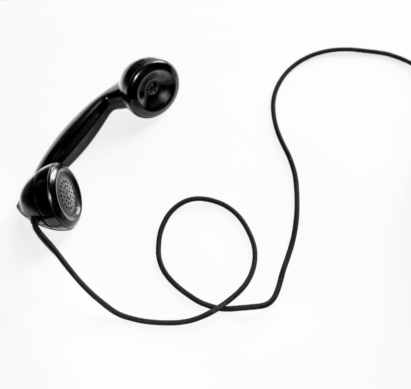 Foto eines schwarzen Wählscheibentelefons vor weißem Hintergrund